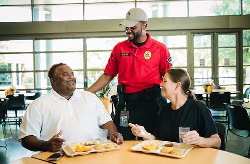 Greeting couple having breakfast, while waiter helps them on campus tour.